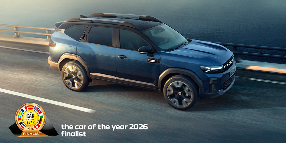Indigo sininen Bigster autotiellä. Lisäksi Car of the Year 2026 -finalistin logo.