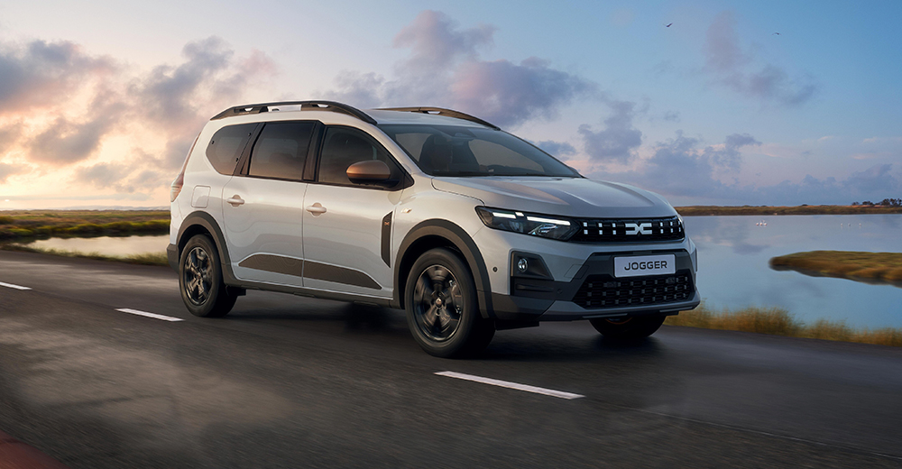 Dacia Jogger keulasta kuvattuna tiellä, jonka oikealla puolella on vesistö.