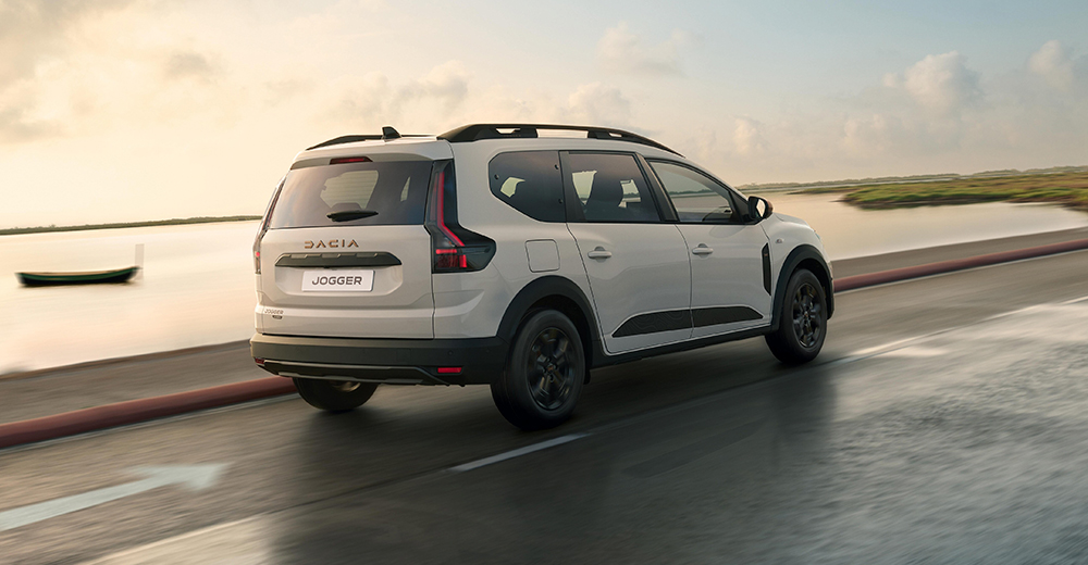 Dacia Jogger takaa kuvattuna tiellä, jonka vieressä on vesistö. 